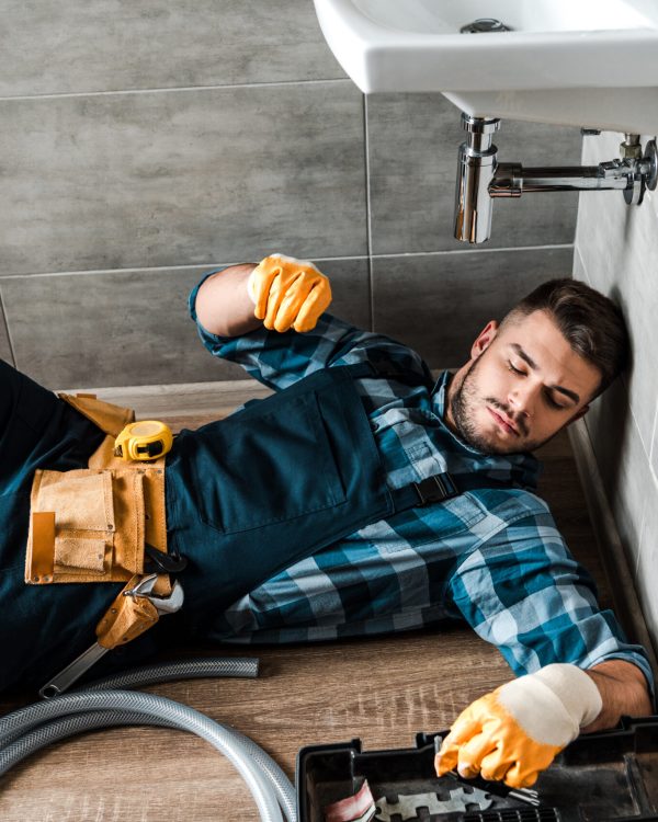 bearded handyman lying on floor near toolbox in bathroom