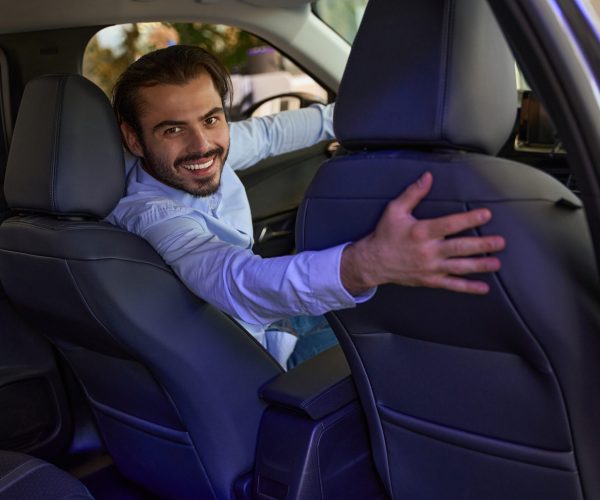 Smiling confident young man sitting in driver seat of new motor vehicle